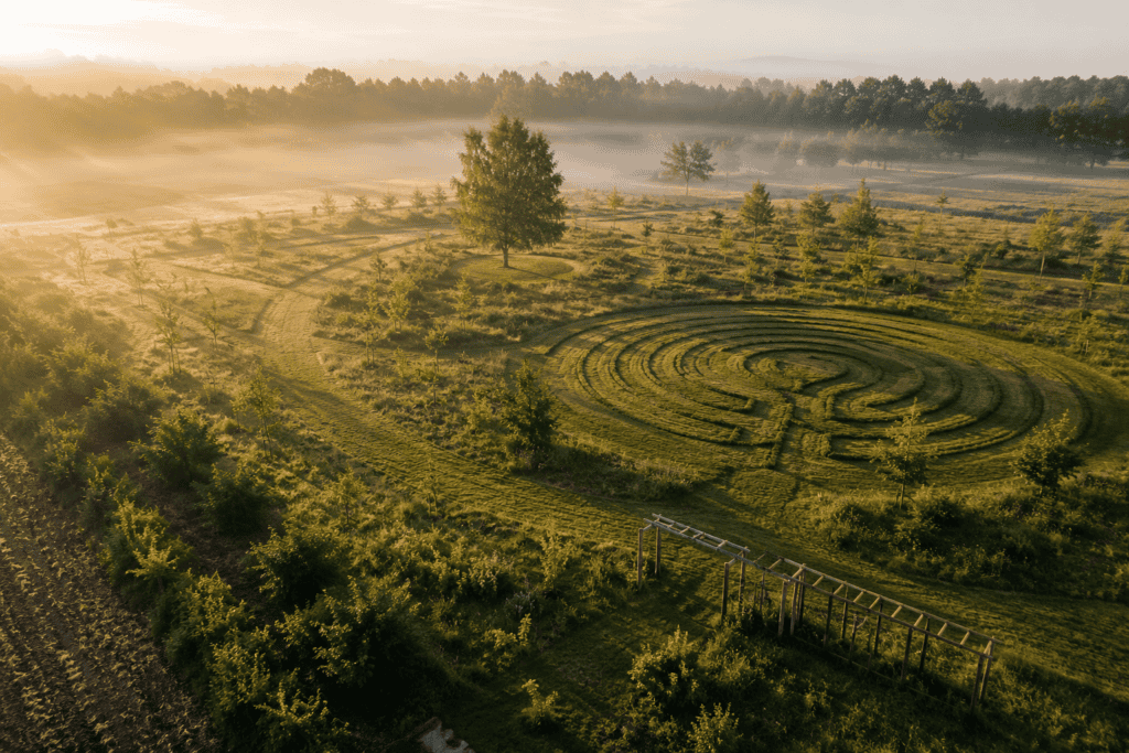 Luchtbeeld van een samenhangend terrein met gemaaid kruidenlabyrint en jonge landschapsstructuren bij Kernlo tijdens ochtendlicht
